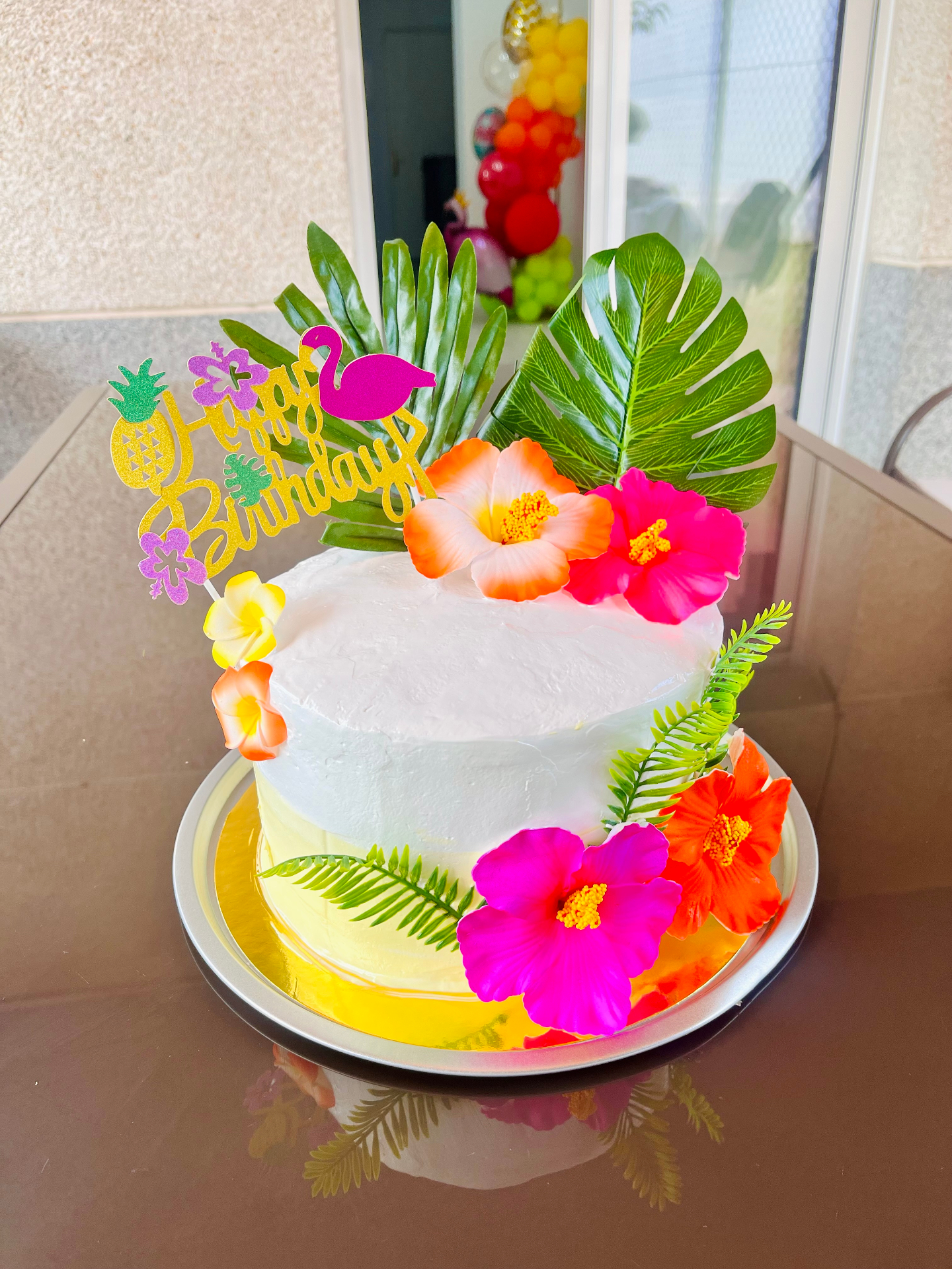 Tarta blanca tropical con hibiscos y hojas de monstera