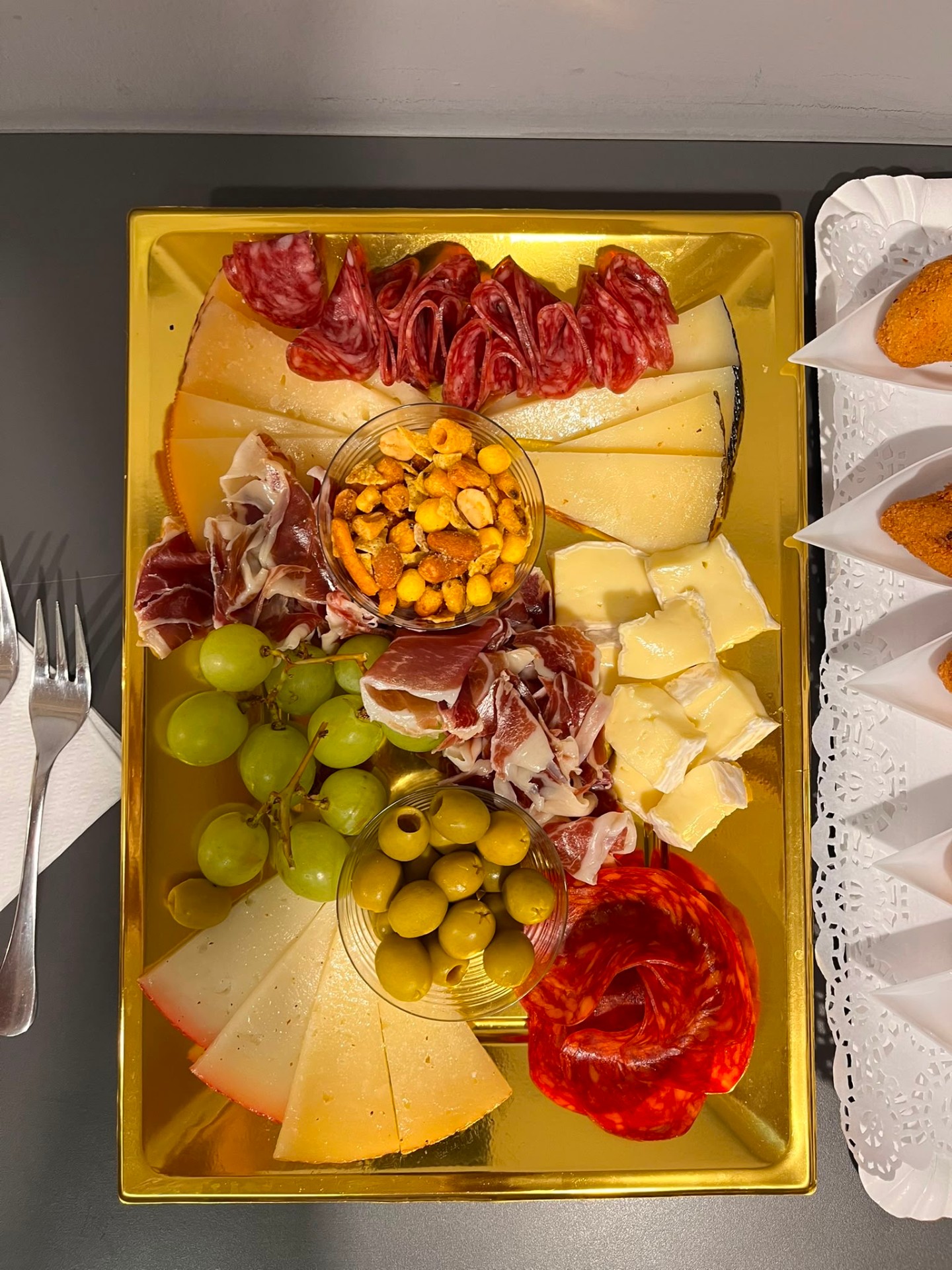 Tabla dorada de quesos, embutidos, aceitunas y uvas